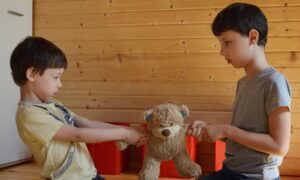 Two kids fight over a teddy bear